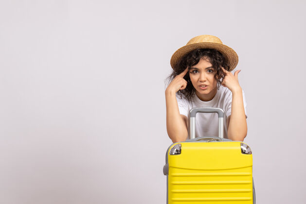 飞行正面图年轻女性带着黄色的包准备在白色的背景上旅行太阳色的航行飞机休息旅游飞行度假美丽年轻女性人