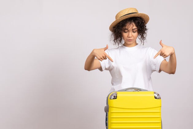 旅行正面图年轻女性带着黄色的包准备乘坐白色背景的航班休息航行旅游度假飞机晒太阳人美丽微笑