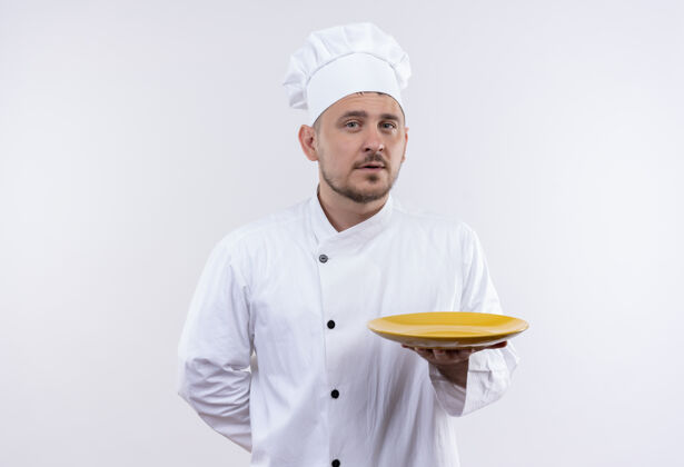 手握自信的年轻帅哥厨师身着厨师制服 拿着盘子隔离在白墙上制服厨艺盘子