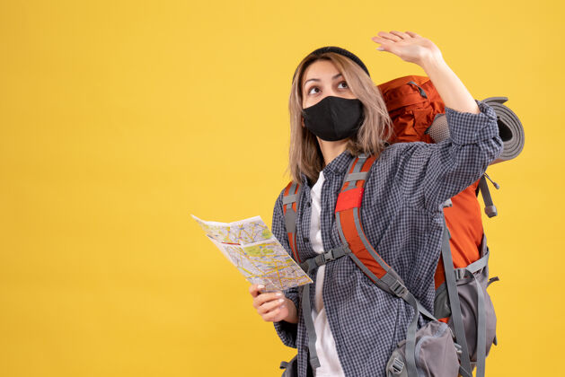 保护套带着黑色面具和背包的旅行女孩拿着地图向上看面具地图黑色