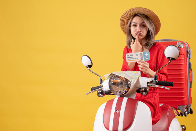 成人一个穿着红衣服的年轻女士坐在轻便摩托车上拿着车票 心烦意乱红衣服玩