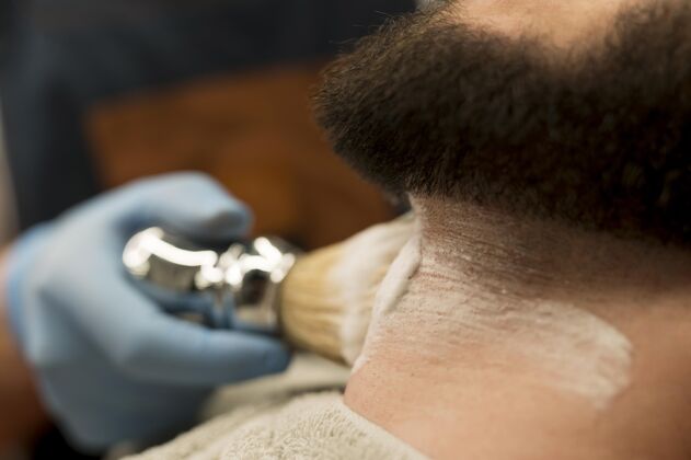 工作理发师用剃须膏勾勒男顾客的胡须轮廓理发师男人职业