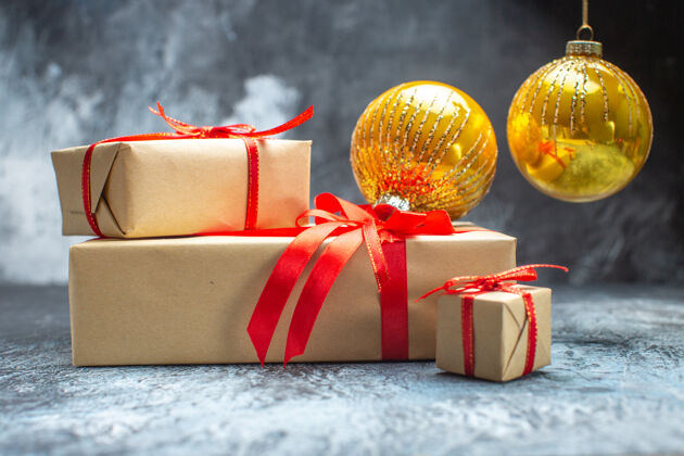圣诞节前视图圣诞礼物与红色蝴蝶结和玩具绑在浅色深色照片新年假期彩色圣诞礼物盒子玩具手镯