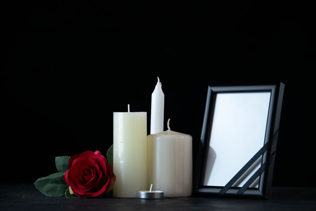 葬礼在黑暗的墙上 白色的蜡烛和红色的玫瑰作为记忆的正视图风景记忆死亡