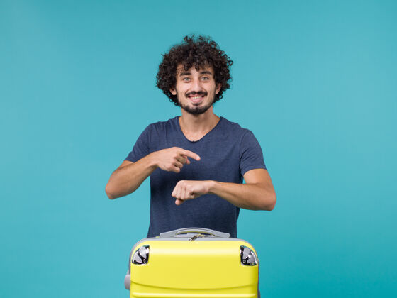 假期度假的男人微笑着 在蓝色上查看时间男性检查手提箱