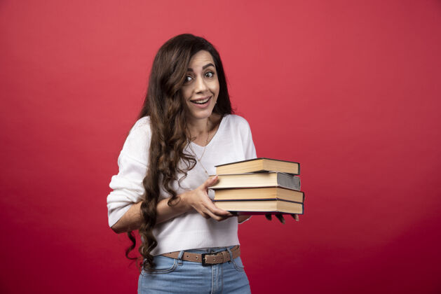 人年轻女子拿着红色背景的书高质量的照片教科书女性女人