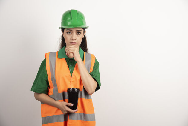 制服年轻的女建造师拿着黑色的杯子高质量的照片女人安全帽