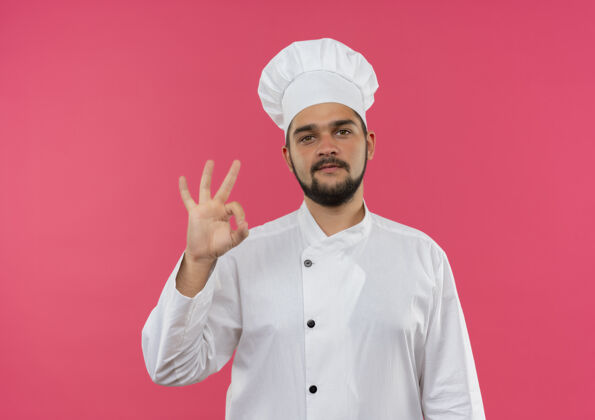 制服自信的年轻男厨师身着厨师制服 在粉红色的墙壁上贴着“做得很好”的牌子 并留有复印空间好的厨师男性