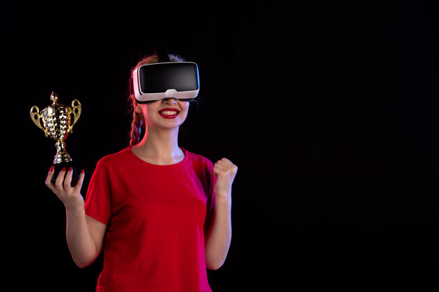 虚拟现实在黑暗的墙壁上 年轻女性正在玩虚拟现实和冠军杯游戏年轻女性赢家