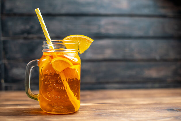 里面正面图新鲜橙汁罐内用吸管放在深色吧台上水果彩色照片饮料液体吸管前面