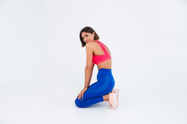 形状适合皮肤黝黑的运动型女性 拥有腹肌 健康曲线 穿着上衣和白色蓝色紧身裤年轻运动员身体