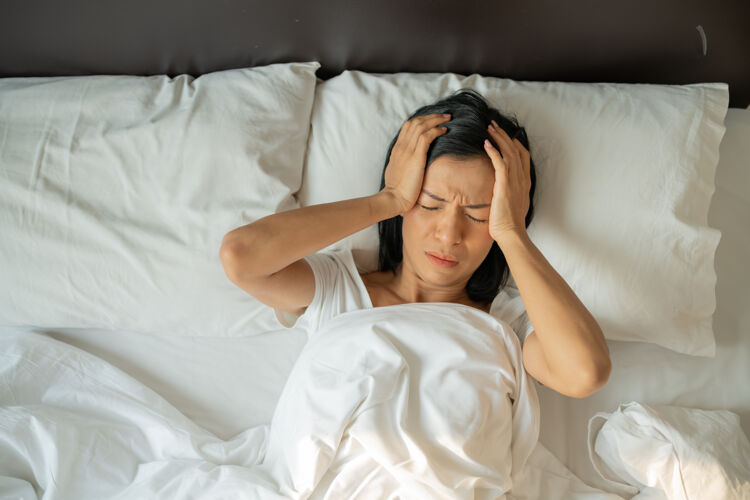 症状不快乐疲惫的熟女闭着眼睛躺在床上 抚摸太阳穴近距离 疲倦的女性患头痛或偏头痛 感觉不适 失眠 睡眠不足人感冒疼痛