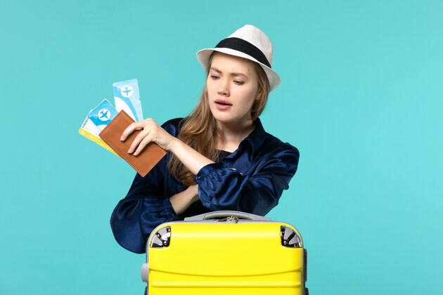 举行前视图年轻女子拿着机票 准备度假检查时间在蓝色背景的旅程远航海上飞机度假准备人微笑