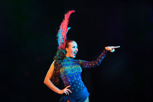 新嘉年华里美丽的年轻女子 霓虹灯下黑色墙壁上羽毛的时尚化装服装人马尔迪里约热内卢
