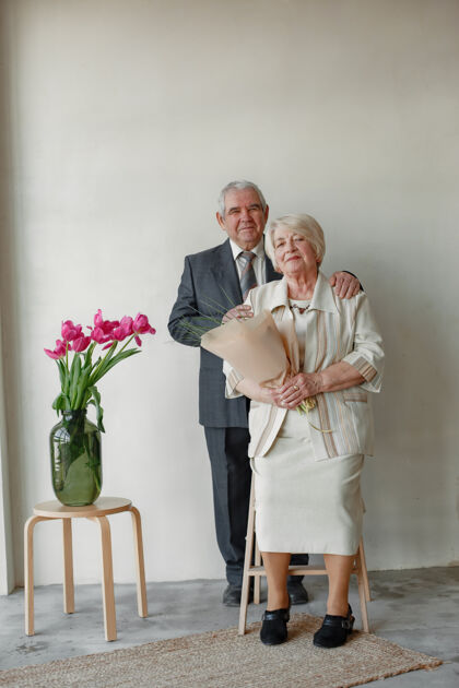 拥抱一对幸福的老夫妇靠着灰墙拥抱的摄影棚肖像关系夫妇爱