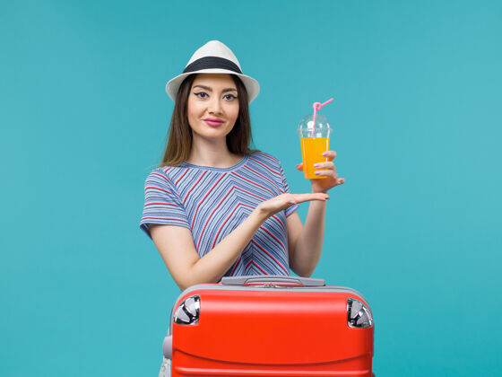 果汁前视图度假妇女与她的红色袋子举行了一次蓝色的背景旅行旅行她的果汁度假女性旅行女性清洁旅行