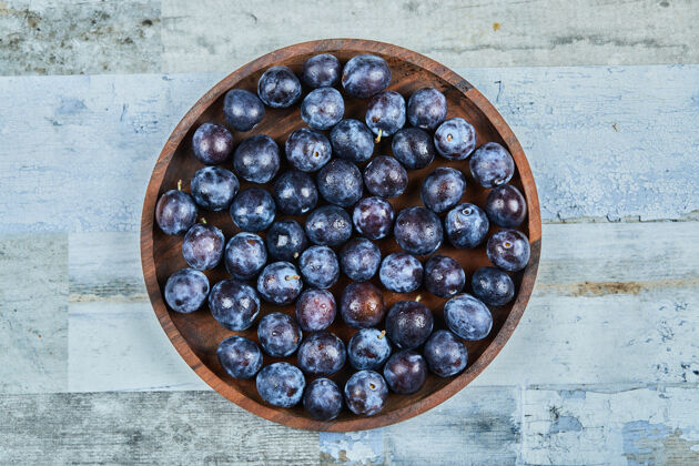 水果把李子放在蓝色盘子里石头花园浆果