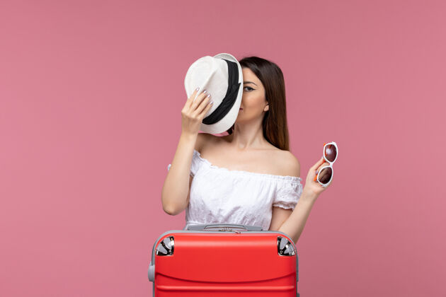 美女正面图：年轻女子戴着帽子在粉色书桌上准备度假旅行出国旅行海上旅行准备帽子旅行