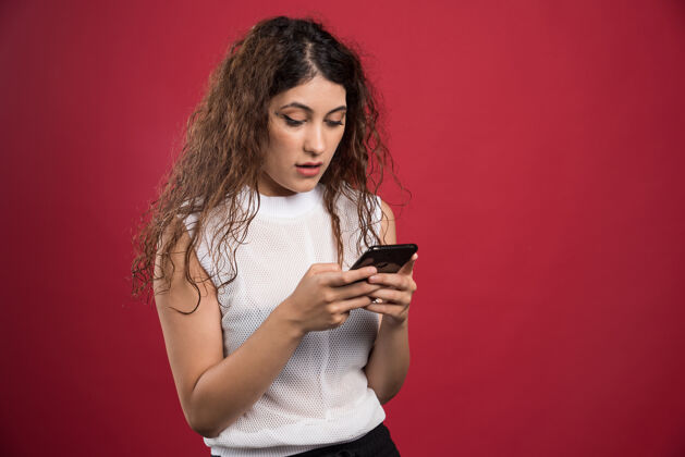 聊天惊讶的女人正在红色的手机上输入什么成人互联网女士