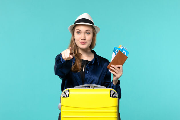 航行前视图年轻女子拿着她的机票 准备在蓝色背景上旅行旅行旅行飞机海上度假旅行准备票人