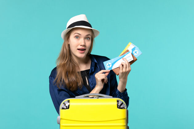 微笑正面图年轻女子拿着机票 准备在蓝色背景上度假海上旅行航程飞机度假准备举行票