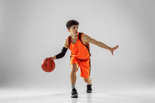 活跃年轻的篮球队员穿着运动服训练 在运动中练习 在运动中奔跑隔离在白墙上大满贯健身房比赛