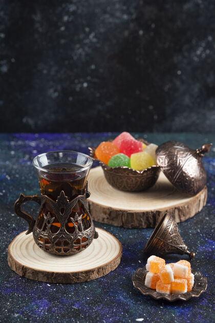 茶壶蓝色表面彩色糖果和香茶的垂直照片液体仪式刷新