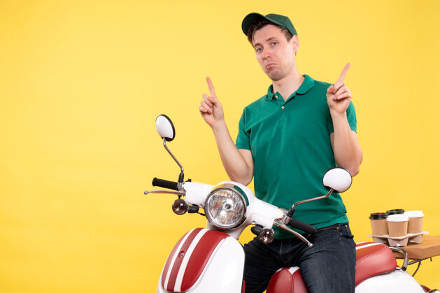 年轻男性信使正面图：穿着绿色制服骑着黄色自行车的年轻男信使人食物工人