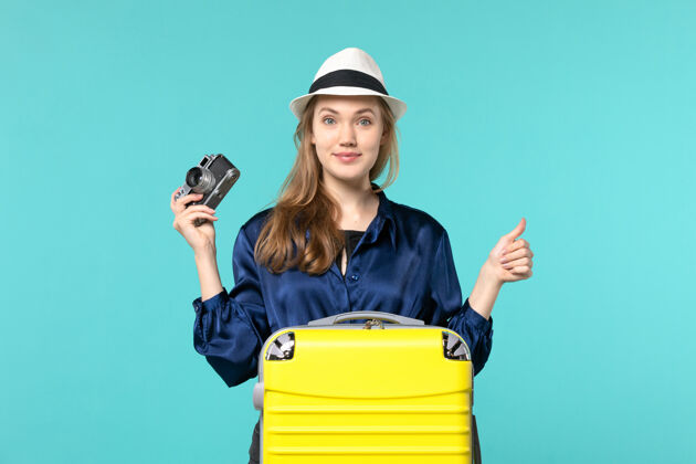 航程前视图年轻女子手持相机在蓝色背景的女子远航海航飞机上成人相机旅程