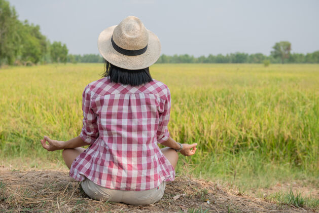 夏天年轻快乐的女人享受着泰国美丽的稻田景色 冥想着 亚洲旅行照片生活方式女人坐在稻田户外练习瑜伽放松田野乡村传统