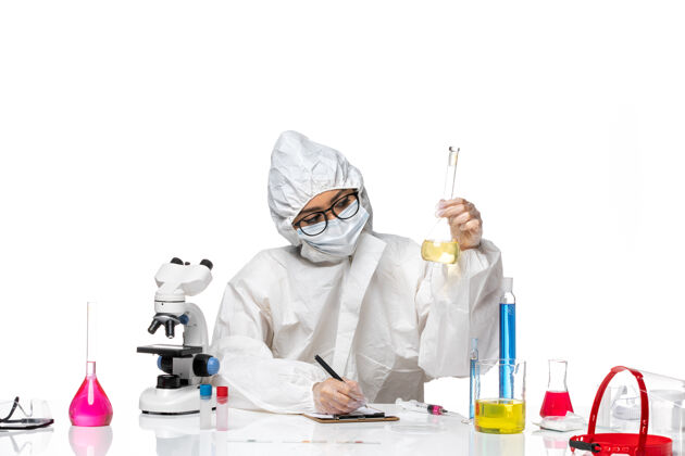面罩正面图身穿特殊防护服的年轻女化学家拿着一个白色背景上的装有溶液的烧瓶实验室病毒化学涂层特殊药品