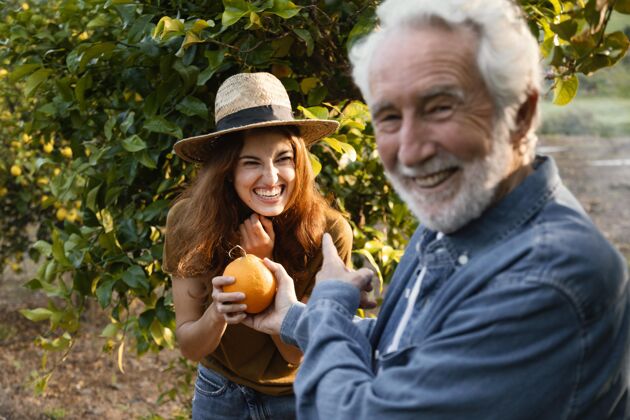 花园一个女人拿着一个新鲜的橘子和她的爸爸柑橘树收获农业