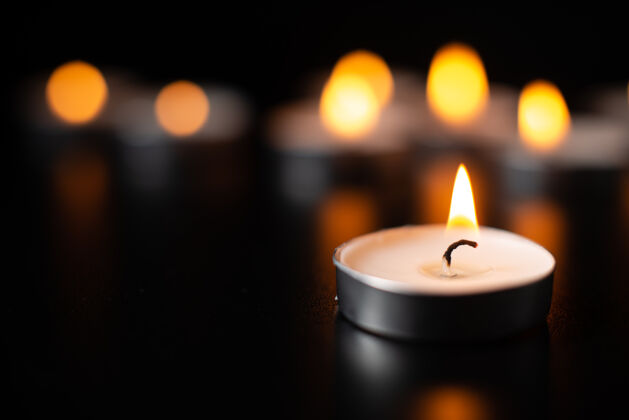 葬礼在漆黑的表面燃烧蜡烛的正面图表面黑暗烛光