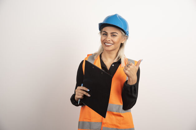 女性女工人用剪贴板在白色背景上竖起大拇指高质量的照片头盔建筑人