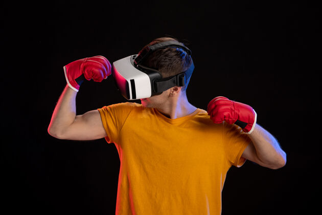 视觉在黑暗的表面上戴着mma手套玩虚拟现实的年轻男性健身游戏运动