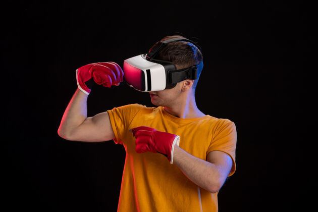 虚拟在黑暗的表面上戴着mma手套玩虚拟现实的年轻男性人黑暗成人