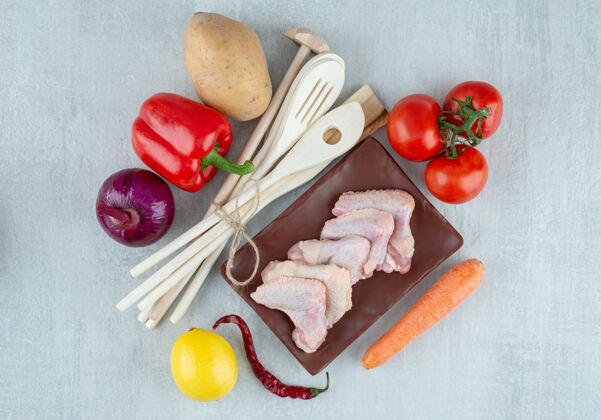 土豆蔬菜 厨房用具和生鸡翅在灰色的表面上木头生的鸡翅