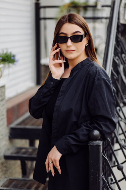 电话开朗漂亮的黑发女人心情好在外面用电话包夹克都市