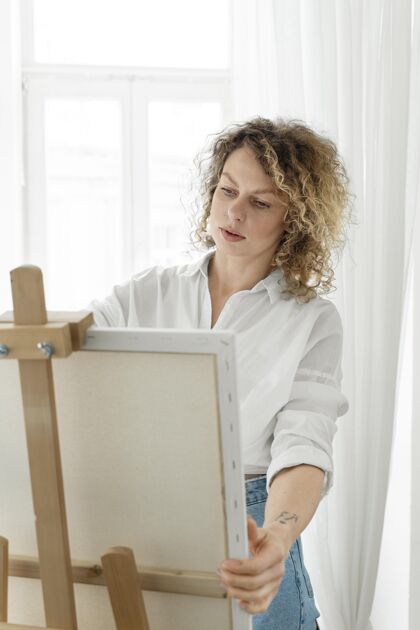 室内卷发金发女人在家画画画架室内活动娱乐