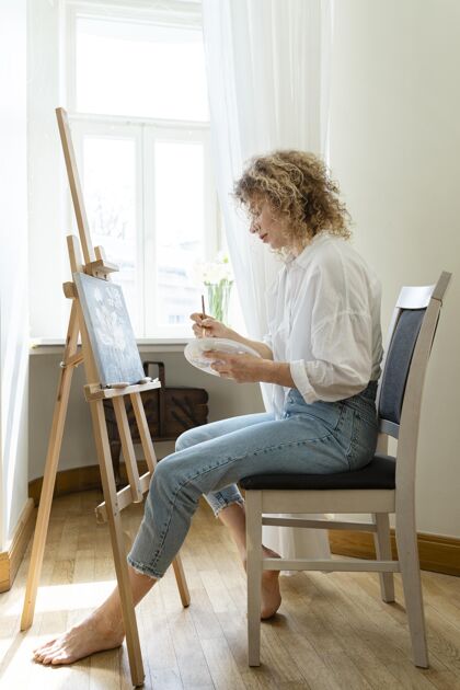 画架卷发女子在家画画侧视图垂直绘画室内活动