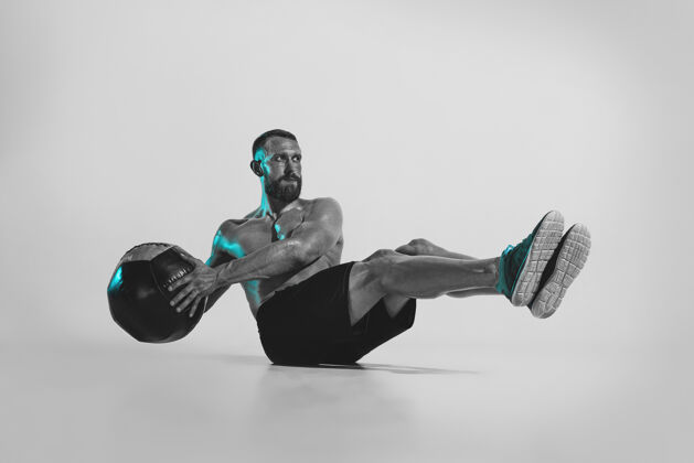 肌肉自我建设年轻的白种人健美训练工作室背景下的霓虹灯肌肉男模特与球概念的运动 健美 健康的生活方式 运动和行动努力训练成人