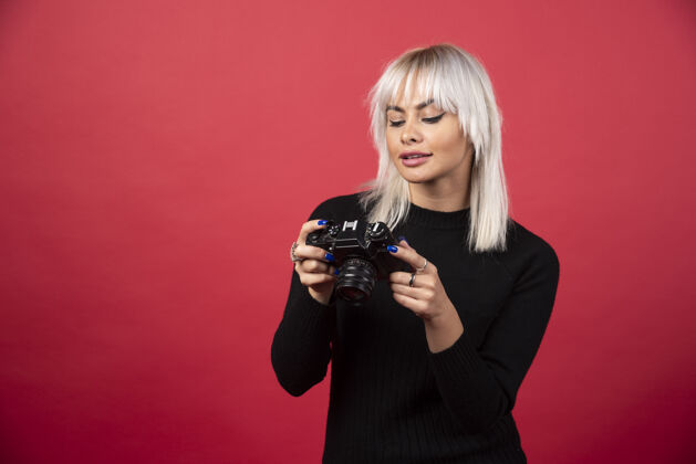 肖像一个年轻的女人在看一个红色背景的相机高质量的照片摄影师手年轻人