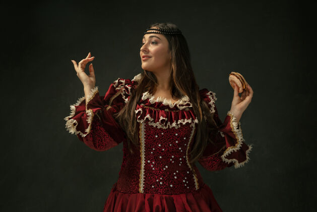 情感初恋身着红色复古服装的中世纪年轻女子的肖像 在深色背景下拿着汉堡包女模特是公爵夫人 皇室成员时代 现代 时尚 美丽的比较概念公主古董紧身胸衣