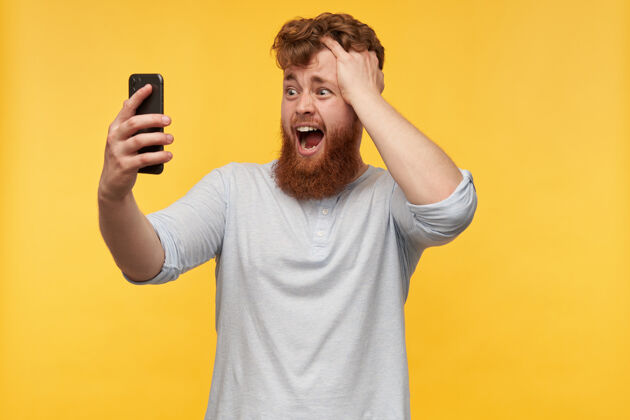 空白年轻人 拿着智能手机 摸着他的头 一副困惑不解的表情出现在屏幕上红发休闲年轻