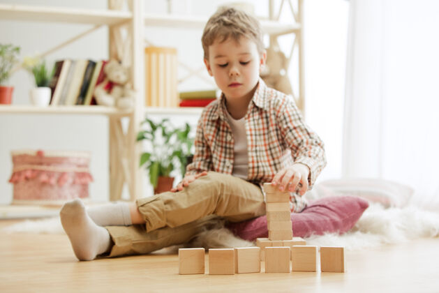 孩子漂亮男孩在家玩木块幼儿园木头游戏