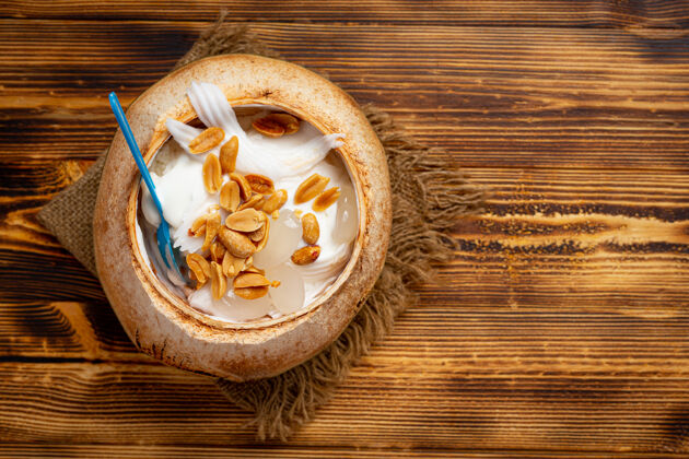 勺子椰奶冰淇淋在椰子壳的深色木质表面冰淇淋滋养美味