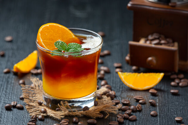 迷迭香橘子和咖啡鸡尾酒在黑暗的表面上玻璃沙漠豆类