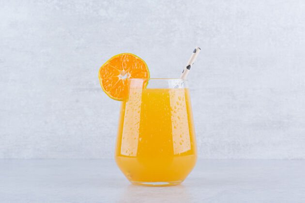 柑橘一杯橙汁 石头上有稻草冷的玻璃杯果汁