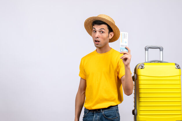 年轻游客正面图年轻的游客戴着草帽站在黄色手提箱旁边拿着票成人持有前面