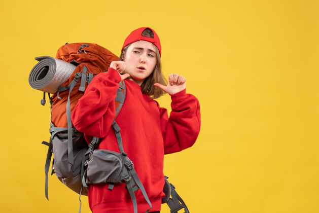 成人正面图年轻的女旅行者背着背包指着自己指向前面背包